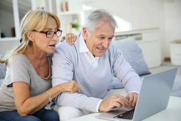 Fototapeta na wymiar Senior couple at home websurfing on laptop computer