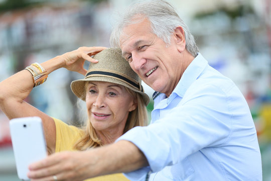 Senior couple of tourists taking picture with smartphone
