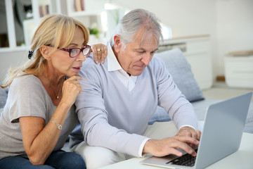 Senior couple at home websurfing on laptop computer
