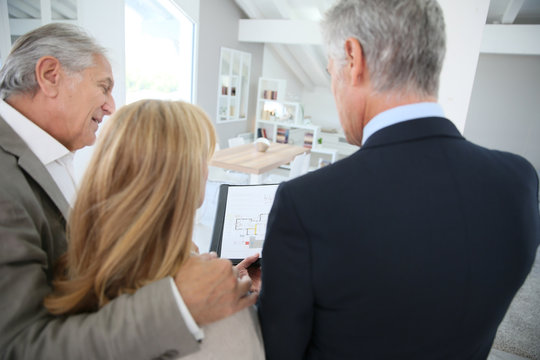 Senior couple with real-estate agent visiting house for sale