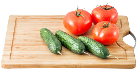 cucumbers and tomatoes on a cutting board isolated on a white background