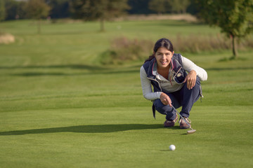 Obraz premium Golferin liest ein Grün vor dem Putten