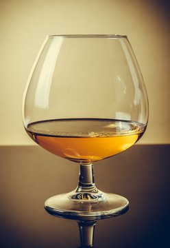 snifter of brandy in elegant typical cognac glass on old fashion style background