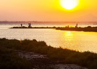 People enjoy seaside fishing and taking pictures at sunset