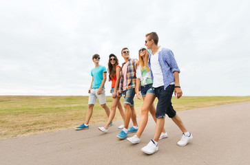 group of smiling friends walking on road