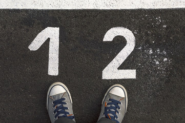 Fototapeta premium Sneakers on asphalt road with 1 and 2 number