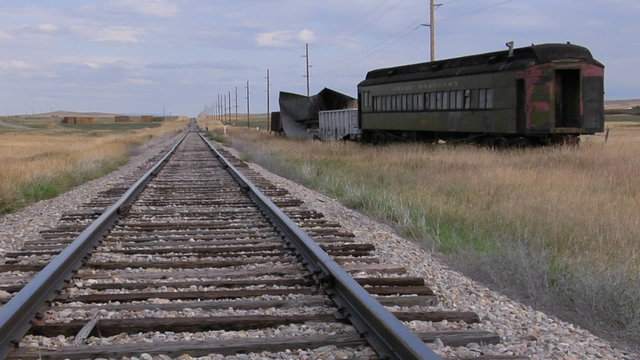 An old abandoned Pullman railway car sits on a siding along a lonely stretch of railroad track.