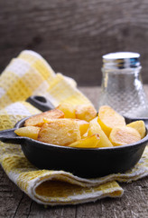 new potatoes fried in a cast iron skillet over an old wooden background