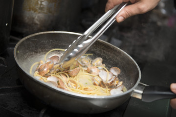 chef is cooking spaghetti alla vongole