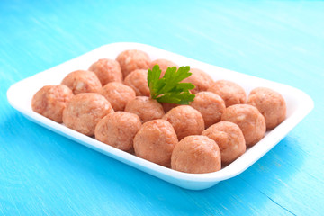 meat balls from raw minced meat in a white tray on a blue background