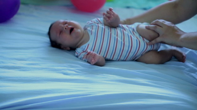Mother's hands turn a child from back to belly.
