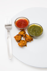 pakora an indian breakfast both vegetarian as well as non vegetarian deep fried served with sauce and green chutney available with clipping path
