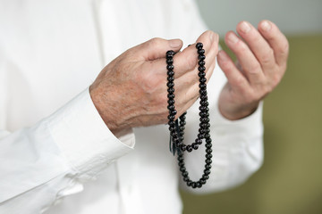 Hands of an old man holding rosary beads