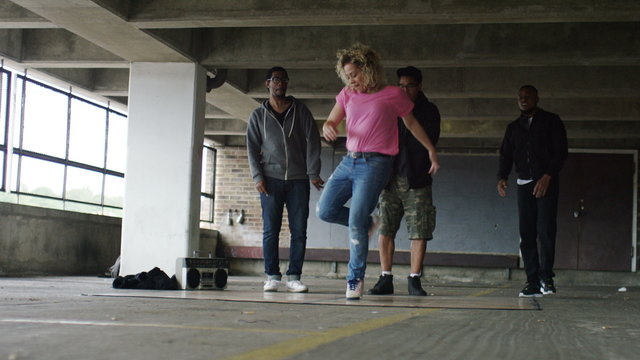 4K Female breakdancer takes to the floor and shows her moves as friends cheer her on, shot on Red Epic Dragon