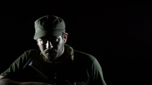 Bearded Soldier Coming out of the Darkness With a Rifle 