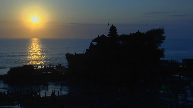 The Pura Tanah Lot temple in Bali, Indonesia is silhouetted against the water.