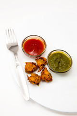 pakora an indian breakfast both vegetarian as well as non vegetarian deep fried served with sauce and green chutney available with clipping path