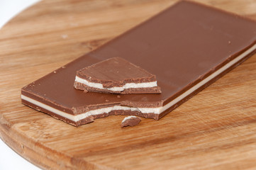 Broken brown white chocolate on the wooden board
