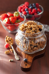homemade healthy granola in glass jar and berries