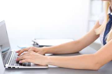 Close up of business woman hands typing on laptop computer, blue tie with polka dots