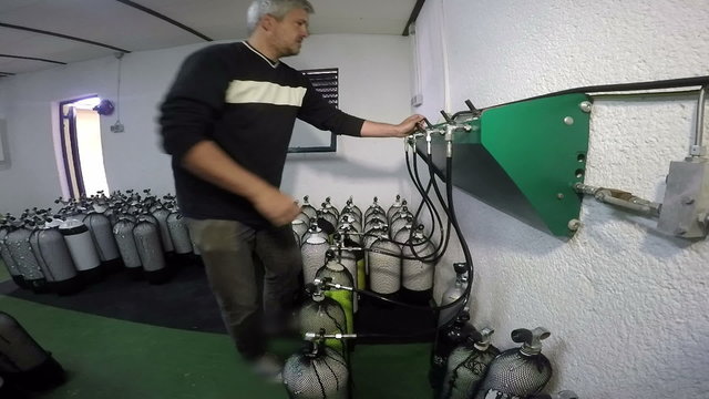 Man Using Diving Air Compressor to Refill Diving Cylinders