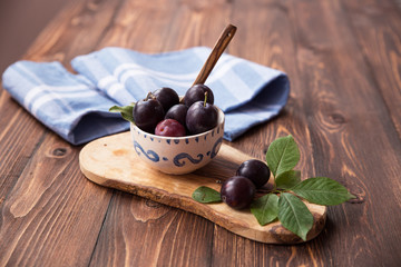 Plums with napkin on wooden table