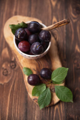 Plums with napkin on wooden table