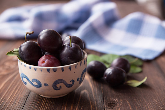 Plums with napkin on wooden table