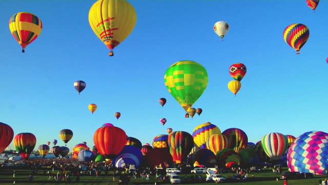Hot air balloons rise against a blue sky at the Albuquerque Balloon Festival.