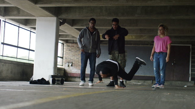 4K Male breakdancer spinning as friends cheer him on, in slow motion, shot on Red Epic Dragon