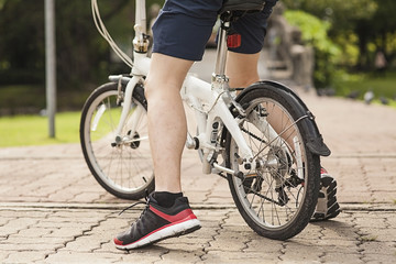 Fototapeta premium Below body of young man stopped by at public park with his bicycle