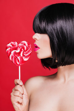 Closeup photo of a beautiful sexy pink lips with lollipop on red