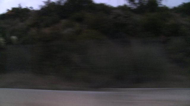 A car travels along Pacific Coast Highway in early morning or late evening as seen through the side window.