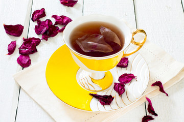 Dried roses and a cup of tea rose on a white wooden background