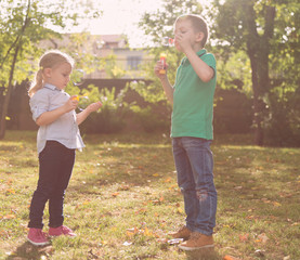 Kids blowing soap bubbles outdoors