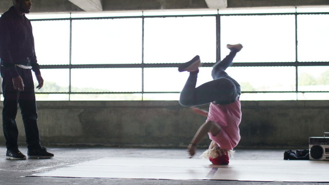 4K Female breakdancer spins on her head as her friend watches on, shot on Red Epic Dragon