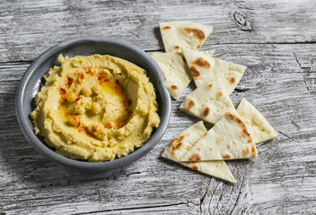 hummus in a ceramic plate on a light wooden surface