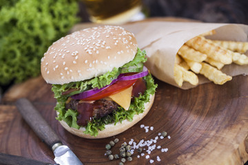 Beef burgers on a wooden board with chips and aromatic spices.
