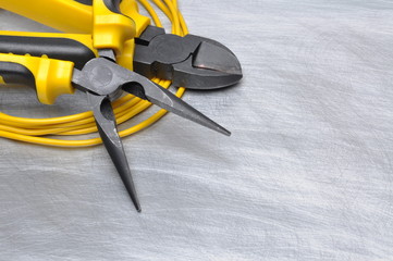 Yellow electrical tools and cables on metal surface with place for text 