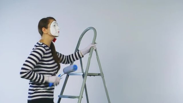 Woman mime standing on a ladder and paint the invisible wall