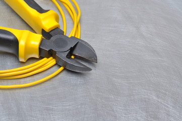 Yellow electrical tools and cables on metal surface with place for text 