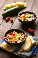 Fresh vegetable salad made of sweet corn, cherry tomato, cucumber, red onion, red pepper, chives, photographed with natural light (Selective Focus, Focus in middle of first bowl)
