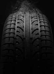 Close-up of car tire with smoke over black background