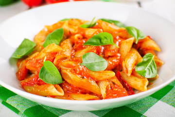 Pasta with tomato sauce and basil on table close up