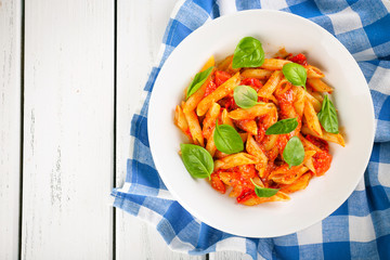 Pasta with tomato sauce and basil on table close up