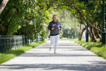 Fototapeta na wymiar Mature woman jogging in the park. Healthy lifestyle