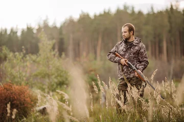 Photo sur Plexiglas Chasser Young male hunter in camouflage clothes ready to hunt  with hunt