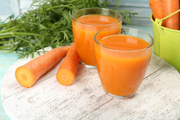 Glasses of carrot juice with vegetables on wooden background