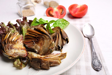 Roasted artichokes on plate, on kitchen table background