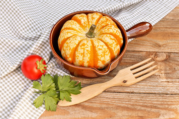 Pumpkin in ceramic pan on wooden background